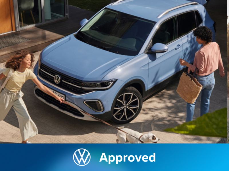 Dos mujeres al lado de un Volkswagen de color azul estacionado