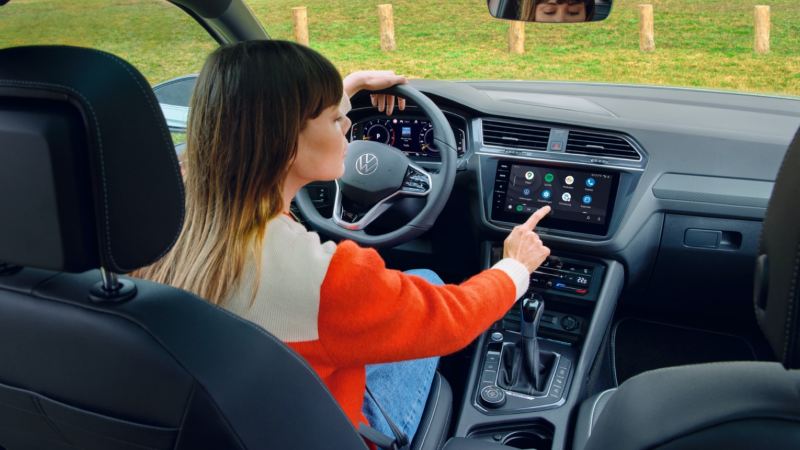 Chica al volante de un Volkswagen Tiguan Allspace vista desde el asiento de atrás