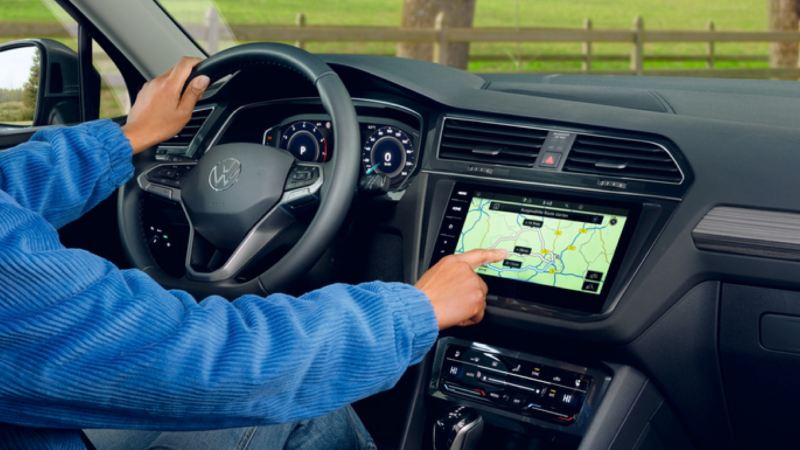 Detalle de un conductor usando la pantalla del salpicadero de un Volkswagen Tiguan Allspace