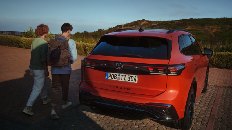 Una pareja al lado de un Volkswagen Tiguan de color rojo vista trasera