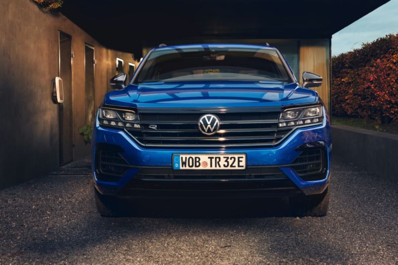 Volkswagen Touareg azul visto de frente aparcado en una casa