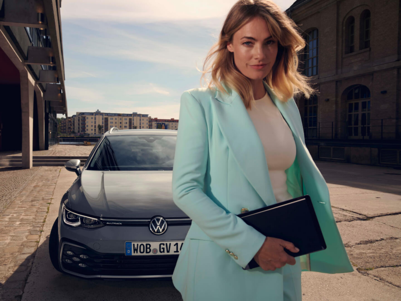 Mujer business frente a Golf Alltrack gris sostiene tablet