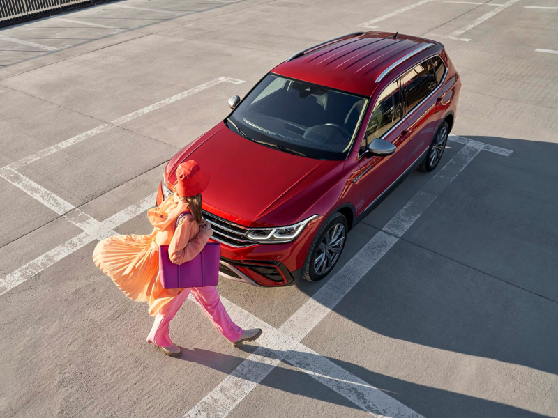 Una mujer camina al lado de un Tiguan Allspace.