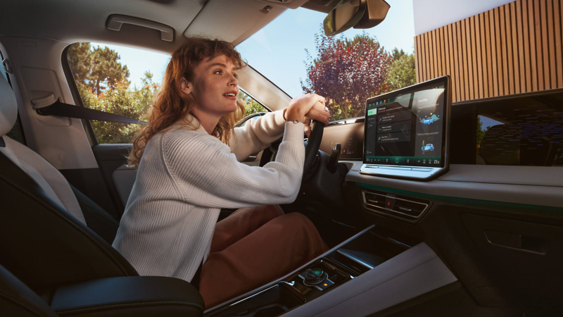 A woman in the driver's seat of a VW looking out at the road ahead