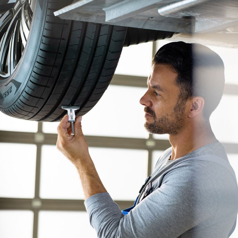 A VW service employee is measuring the tyre tread depth