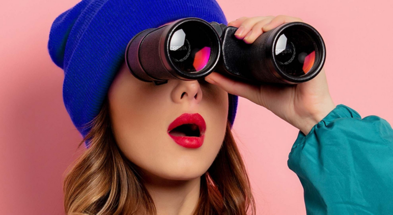 Imagen de chica con binoculares apuntando su mirada hacia el sur.