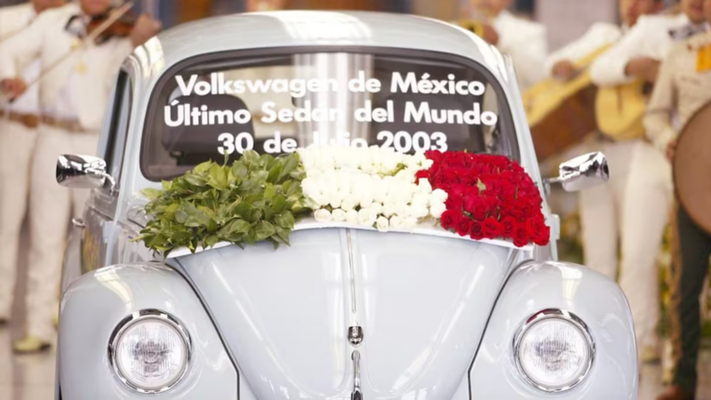 Último Volkswagen Sedán fabricado en México decorado con flores en colores de la bandera mexicana y mariachis.