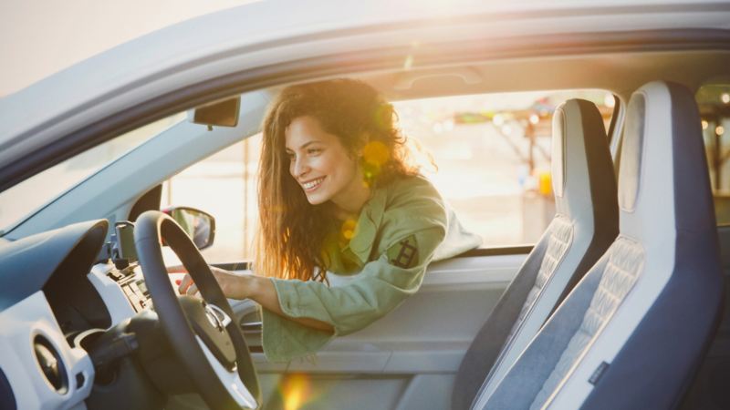 Frau lehnt sich durch Fahrzeugfenster – Kilometerleasing