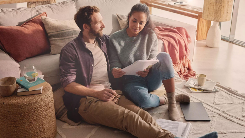 Un homme et une femme sont assis dans un salon en train de regarder des documents.