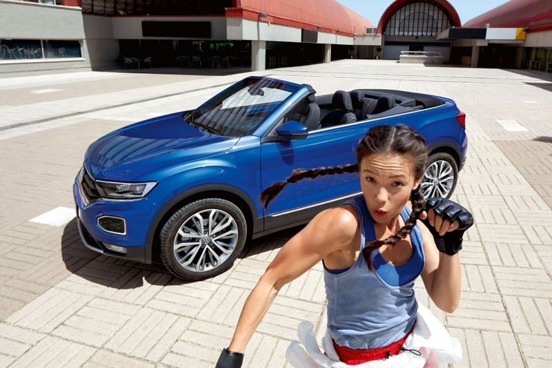 A woman dancing in front of a T-Roc Cabriolet soft top