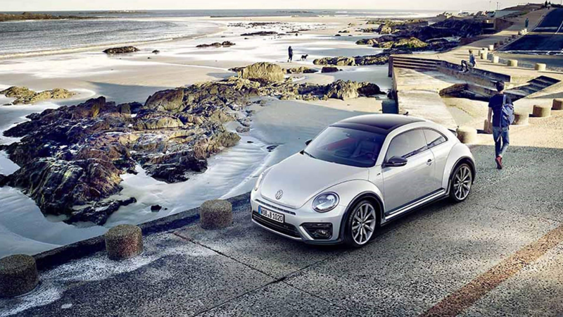 A Beetle car parked by a coastline