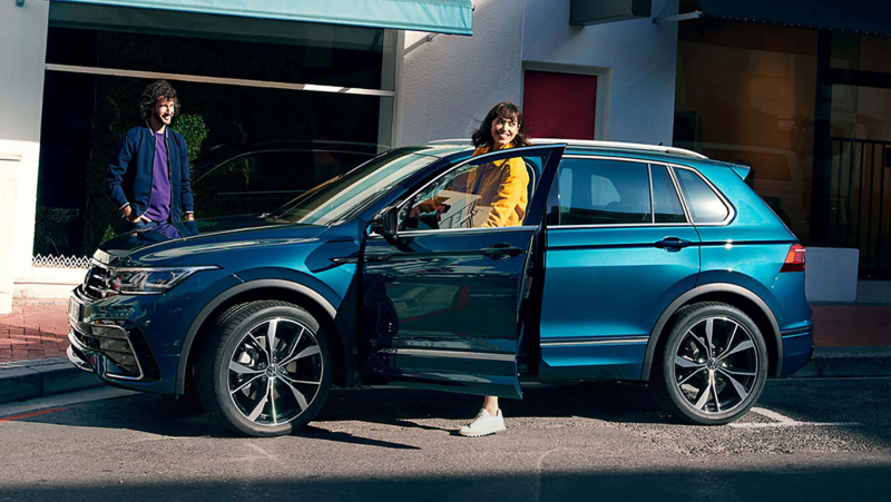 A woman getting into a blue VW Tiguan