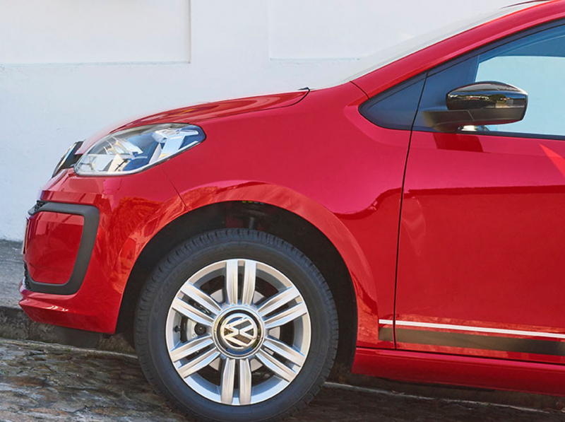 Red Volkswagen up! parked on a steep cobbled street.