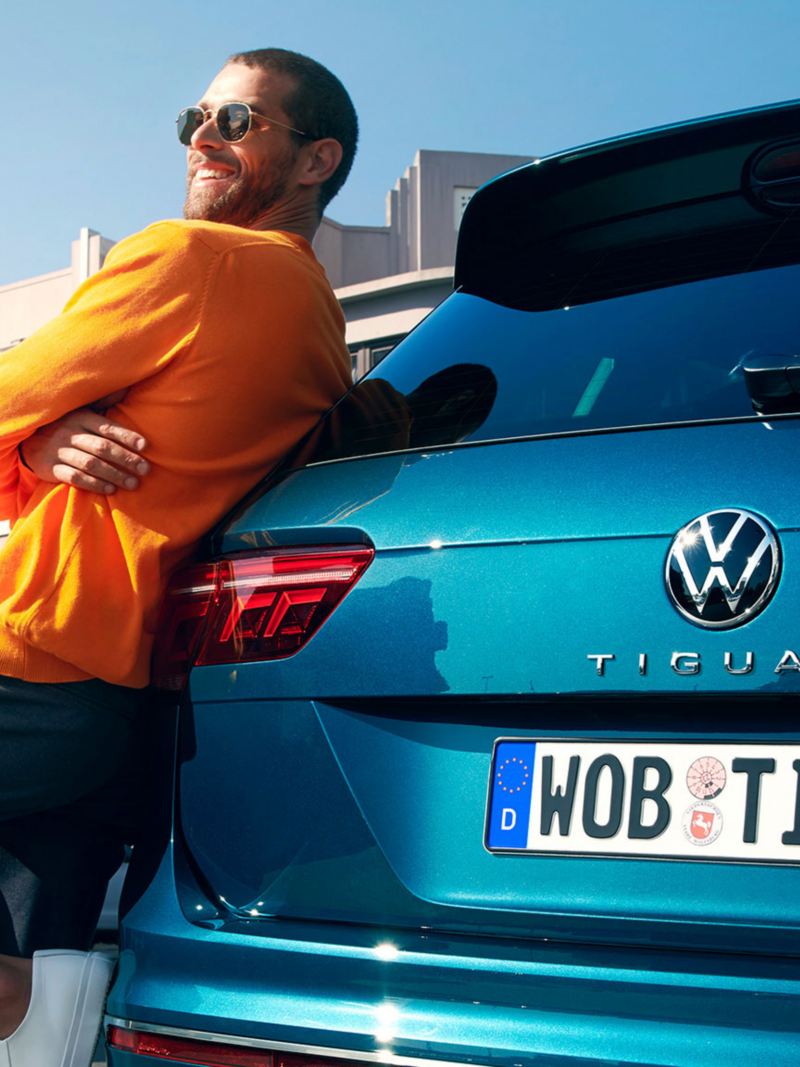 A man leaning against the boot of a Blue New Tiguan.