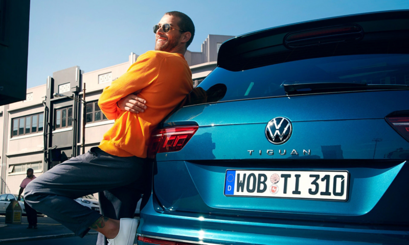 A man leaning against the boot of a Blue New Tiguan.