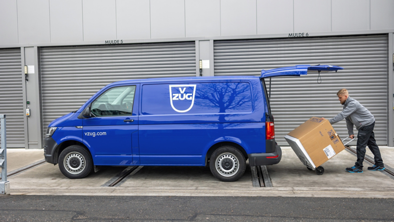 Ein Servicetechniker von V-Zug lädt ein Karton aus dem VW Transporter aus