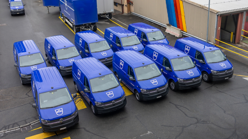 Von oben sind mehrere VW Transporter von V-Zug, welche auf einem Platz parkiert sind, ersichtlich