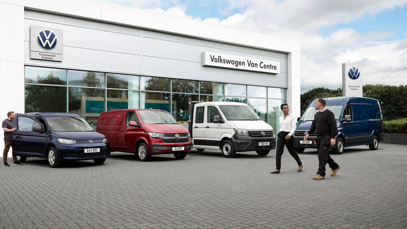 Two people walking past a range of a Van centre and a range vans 