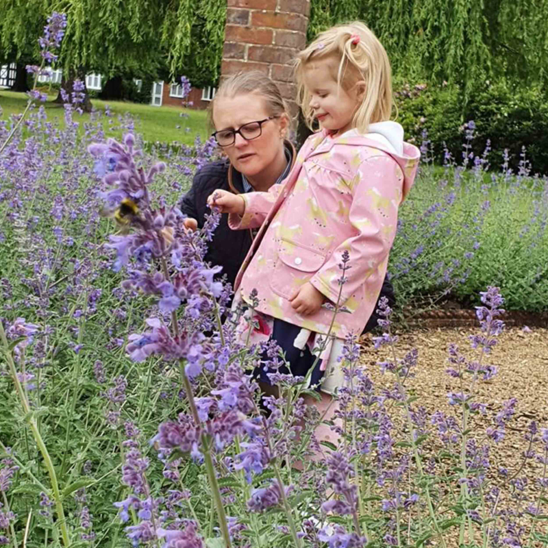 Photo showing a woman and a little girl looking at some flowers.