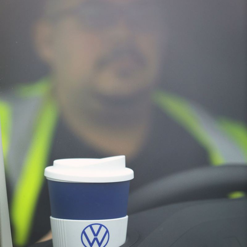 Closeup of a coffee cup on top of a VW van dashboard.