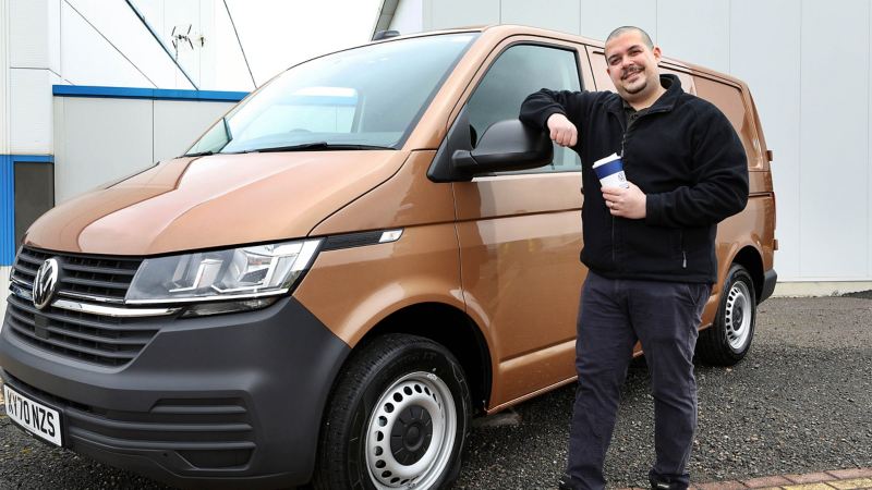 A driver standing next to a VW van.