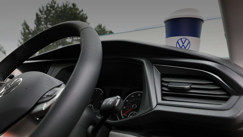 A tight shot of a coffee cup sitting on a VW Vans dashboard.