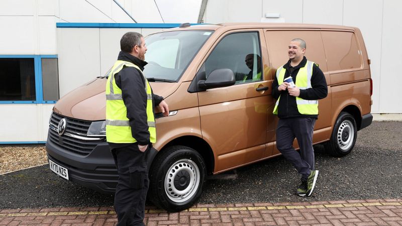 Two van drivers standing next to a VW Van.