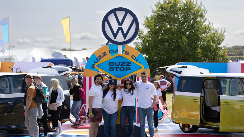 Photo showing event staff standing under a Volkswagen sign. 