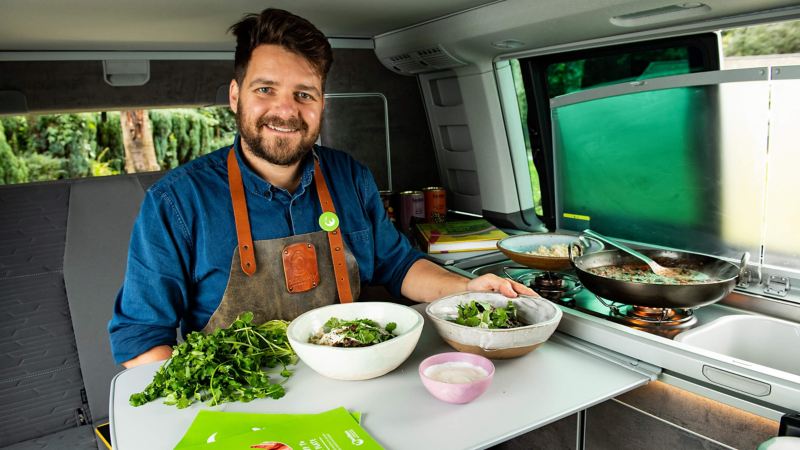 Chef Tom sitting inside a California camper van with some ingredients