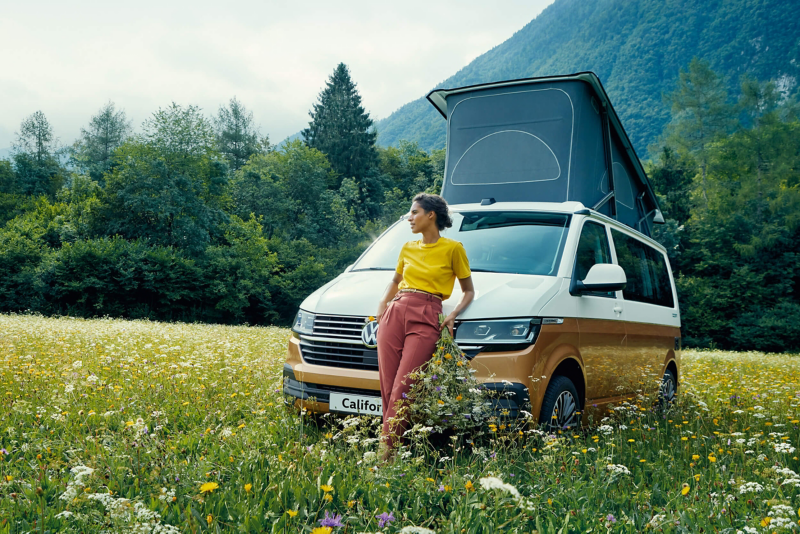 A woman leaning on a Grand California in a field