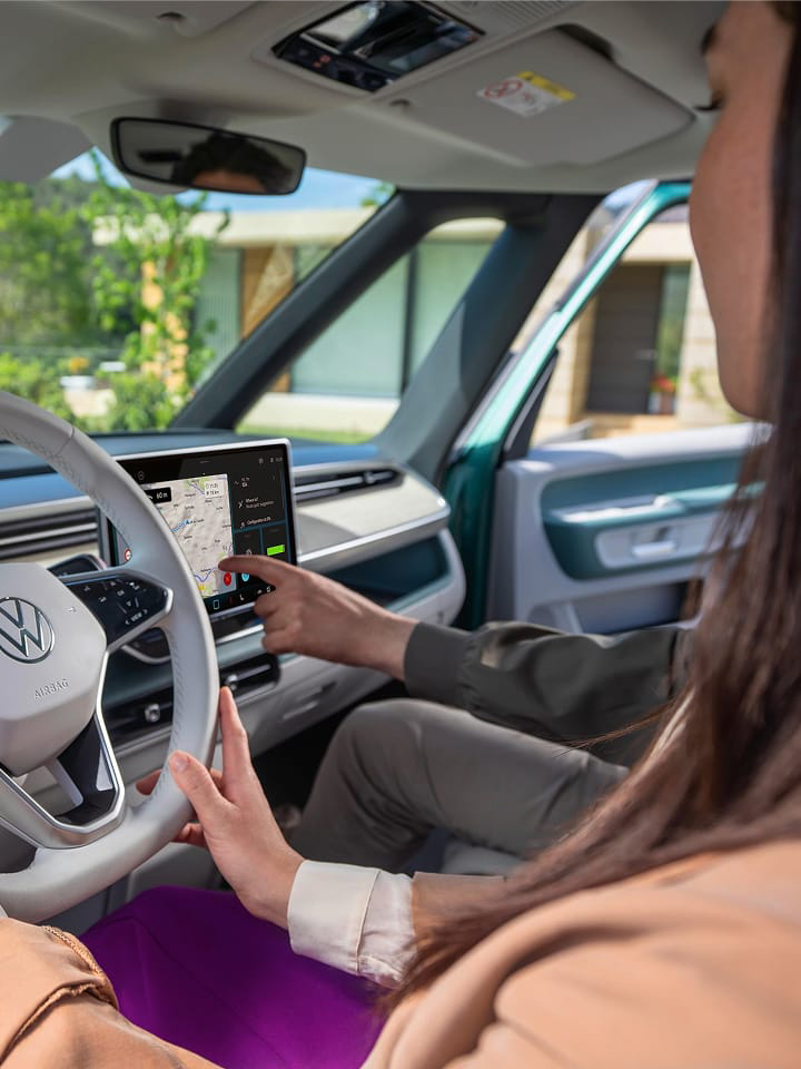 Una mujer al volante de una furgo de Volkswagen.