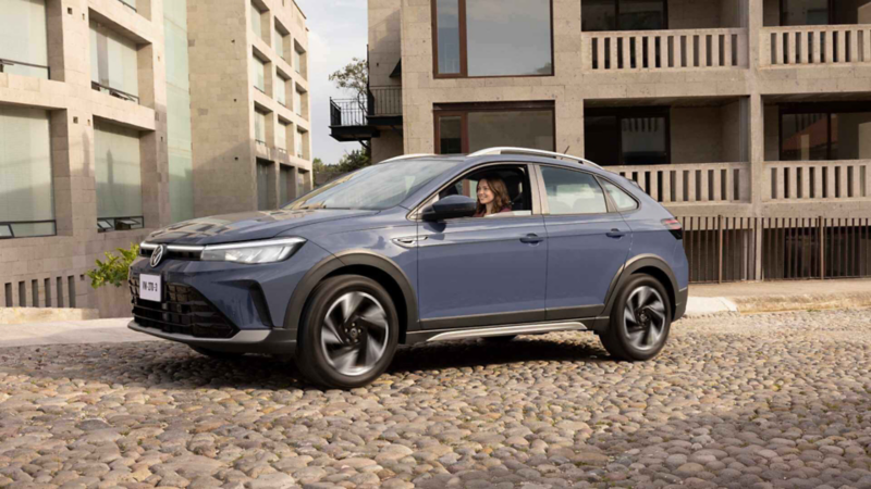 Nivus de Volkswagen de color azul titán estacionada cerca de edificios de concreto. 