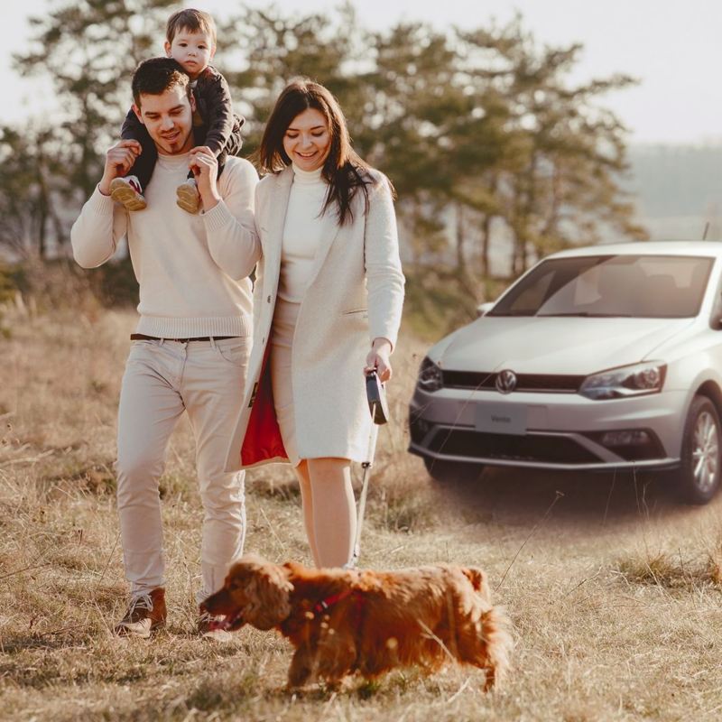 Imagen de familia vacacionando en el bosque junto con un auto Vento VW.
