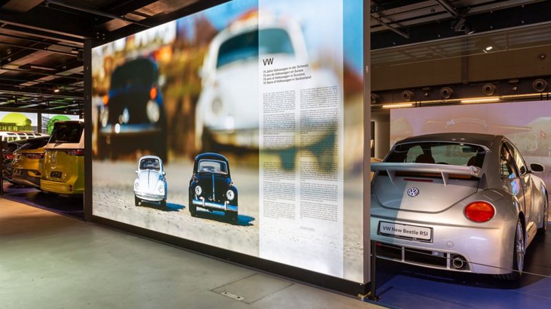 Un Maggiolino VW accanto a un cartello sulla storia della Volkswagen