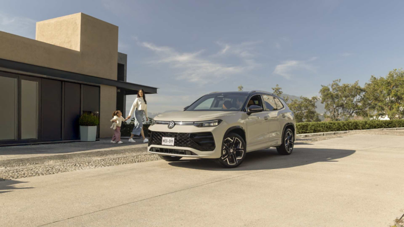 Familia camina hacia un SUVW Tiguan 2025 en color exterior blanco y techo negro. 