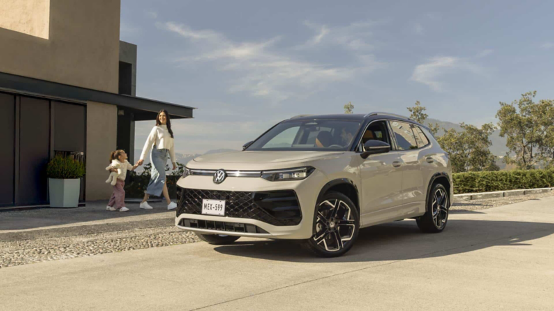 Mamá e hija caminan hacia un SUVW Tiguan 2025 en color exterior blanco y techo negro. 
