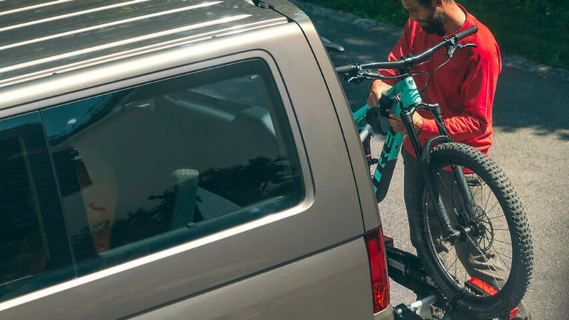 Un uomo carica la bicicletta nel porta biciclette montato sul retro del suo veicolo.