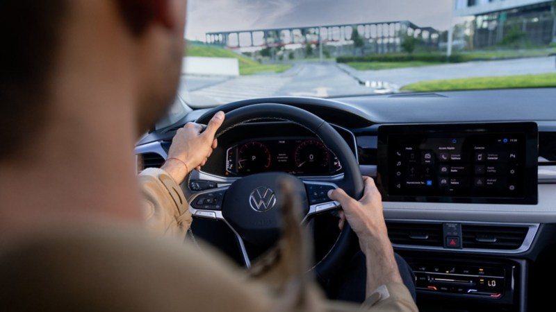 Conductor al volante en el interior de un Volkswagen, con pantalla táctil y digital cockpit.
