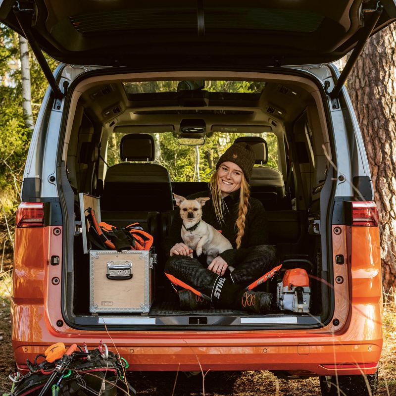 Victoria Carstens bak i en VW Multivan eHybrid minibuss med hunden Stanley i knät