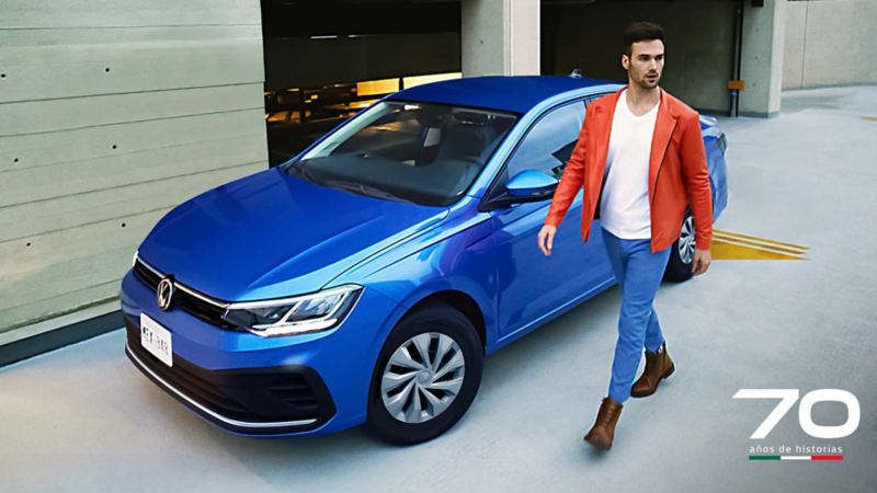 Joven camina a lado de un auto azul Volkswagen, Virtus 2024. 