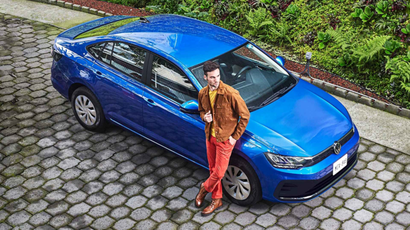 Virtus 2024 de Volkswagen en color azul, con hombre que posa sobre auto sedán.