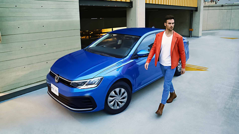 Virtus 2023 en color azul, con hombre que camina a lado del auto sedán. 