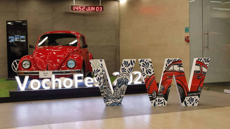 Letras gigantes de Vocho Fest decoradas junto a Volkswagen Sedan de color rojo.