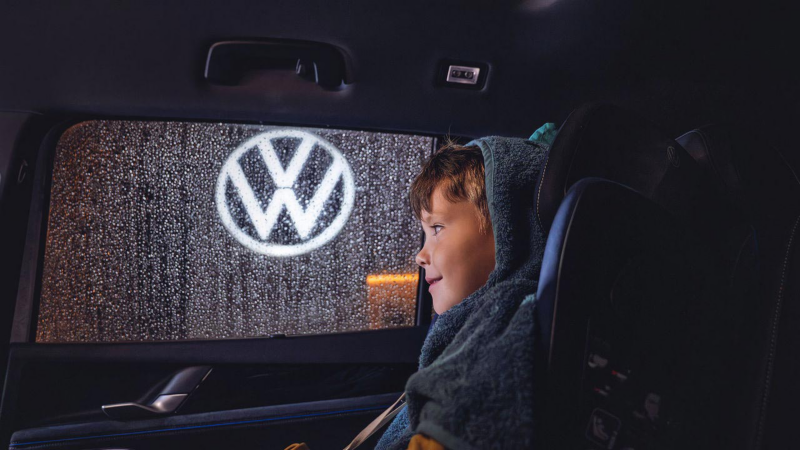 Un enfant à la fenêtre dans une voiture avec un logo VW