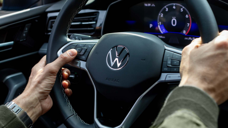 Manos sujetan el volante de un Jetta frente al tablero digital.Modificado con inteligencia artificial