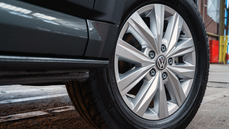 Zilverkleurige lichtmetalen velg met het Volkswagen-logo op een grijze bedrijfswagen.