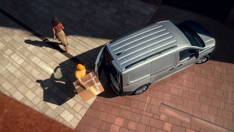 Caddy de Volkswagen en color gris - Trabajador saca mercancía de cabina. 