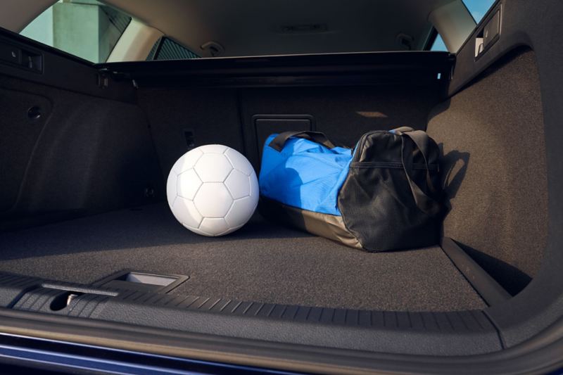 Interior de cajuela de camioneta SUV de Volkswagen, con balón de futbol y maleta deportiva. 