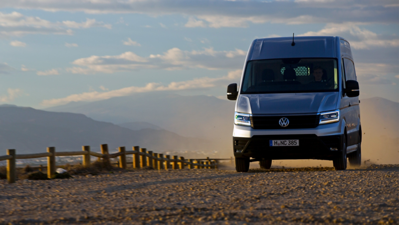 VW Crafter lätt lastbil kör på en grusväg längsmed ett lågt staket