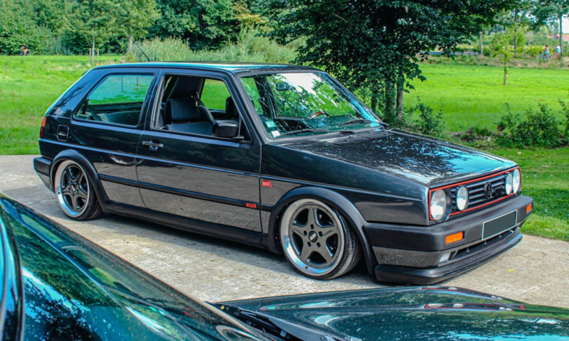 Volkswagen Golf GTD noire customisée stationnée devant un parc.